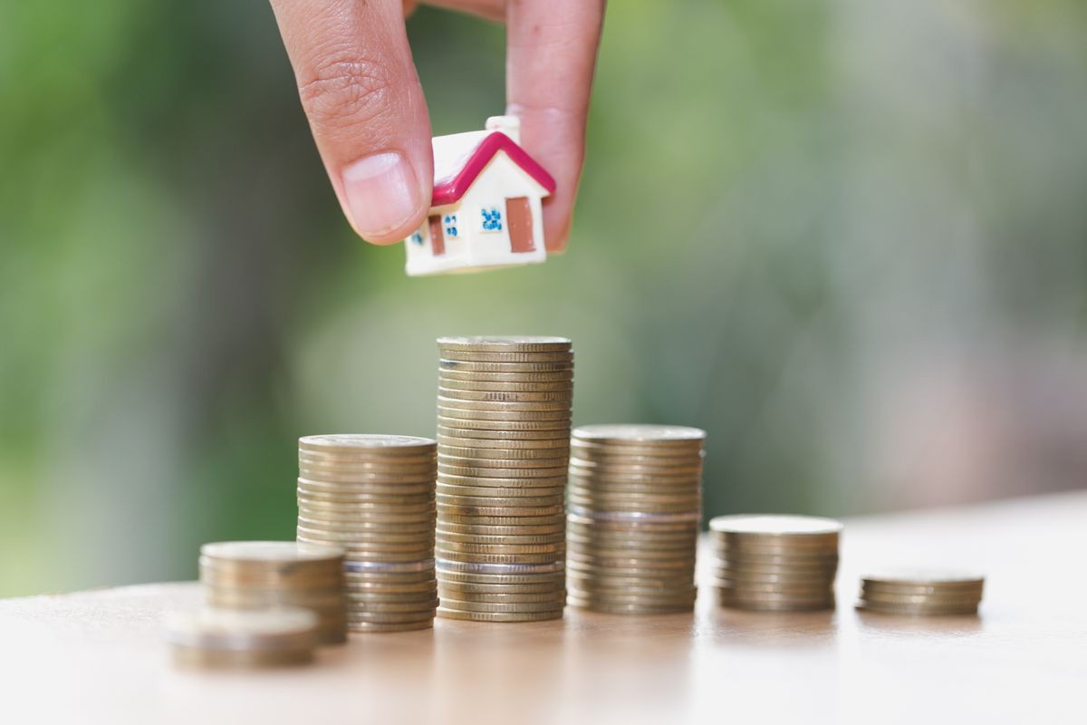 Woman hand hold a  home model put on the stack coin with growing, Savings money for buy house and loan to business investment for real estate concept. Invesment and Risk Management.